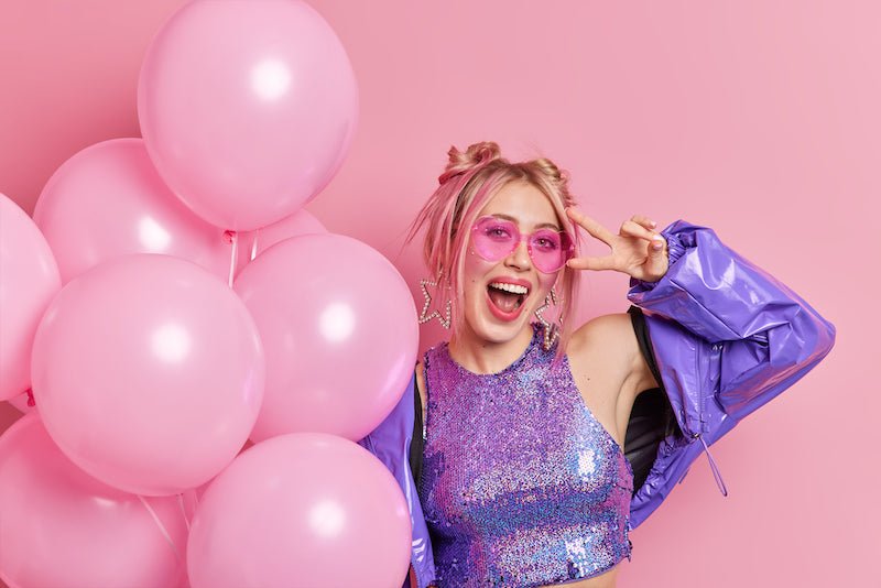 Pink and purple balloons and woman in sparkly purple top for fun birthday at Parte Haus party supply store in Bethesda Maryland
