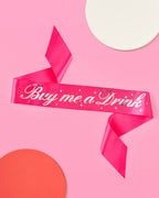 Hot pink Buy Me a Drink sash with silver lettering for bachelorette party from Parte Haus party supply store in Bethesda MD