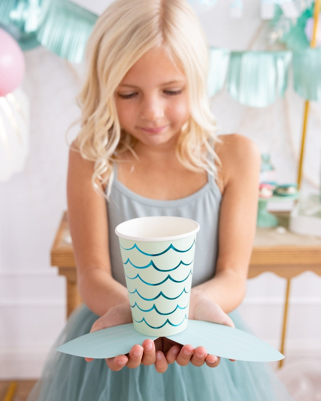 Blue mermaid paper cup and tail held by girl undersea birthday theme from Parte Haus party supply store in Bethesda MD