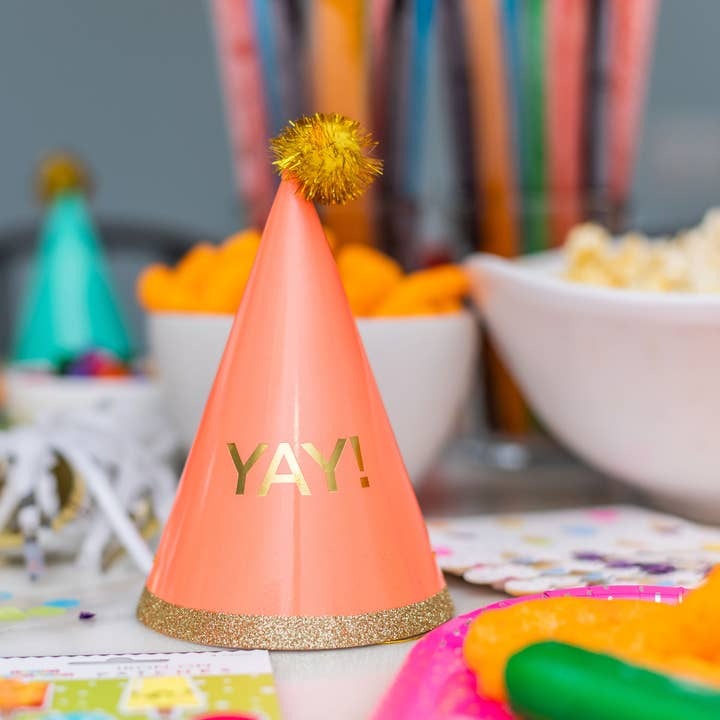 Peach cone birthday hat with gold trim and pompom fun table decor for celebration from Parte Haus party supply store in Bethesda MD