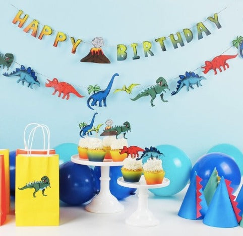 Colorful dinosaur themed birthday decorations with balloons hats and cupcake toppers from Parte Haus party supply store in Bethesda MD.
