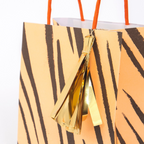 orange tiger stripe gift bag with gold tassel for jungle birthday from Parte Haus party supply store in Bethesda MD