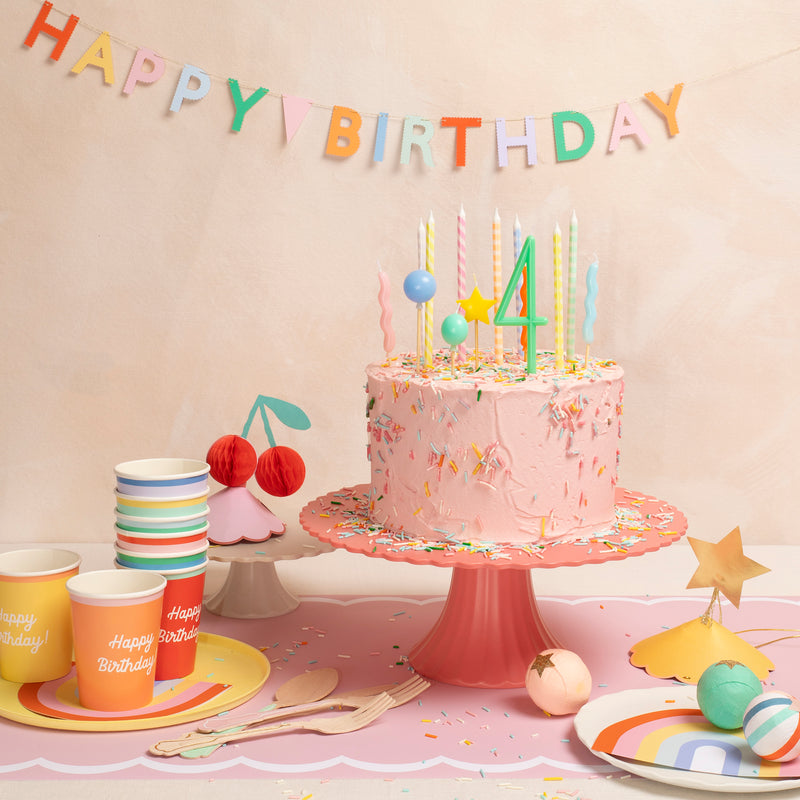 Pink rainbow birthday cake with candles and pastel tableware for kids party from Parte Haus party supply store in Bethesda MD