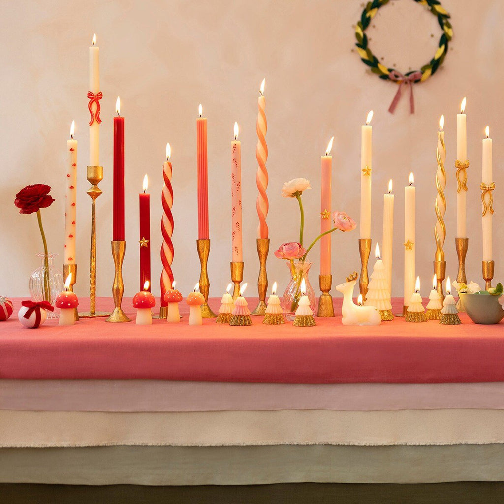 Red and pink taper candles with gold holders on a decorated table for holiday celebration from Parte Haus party supply store in Bethesda MD