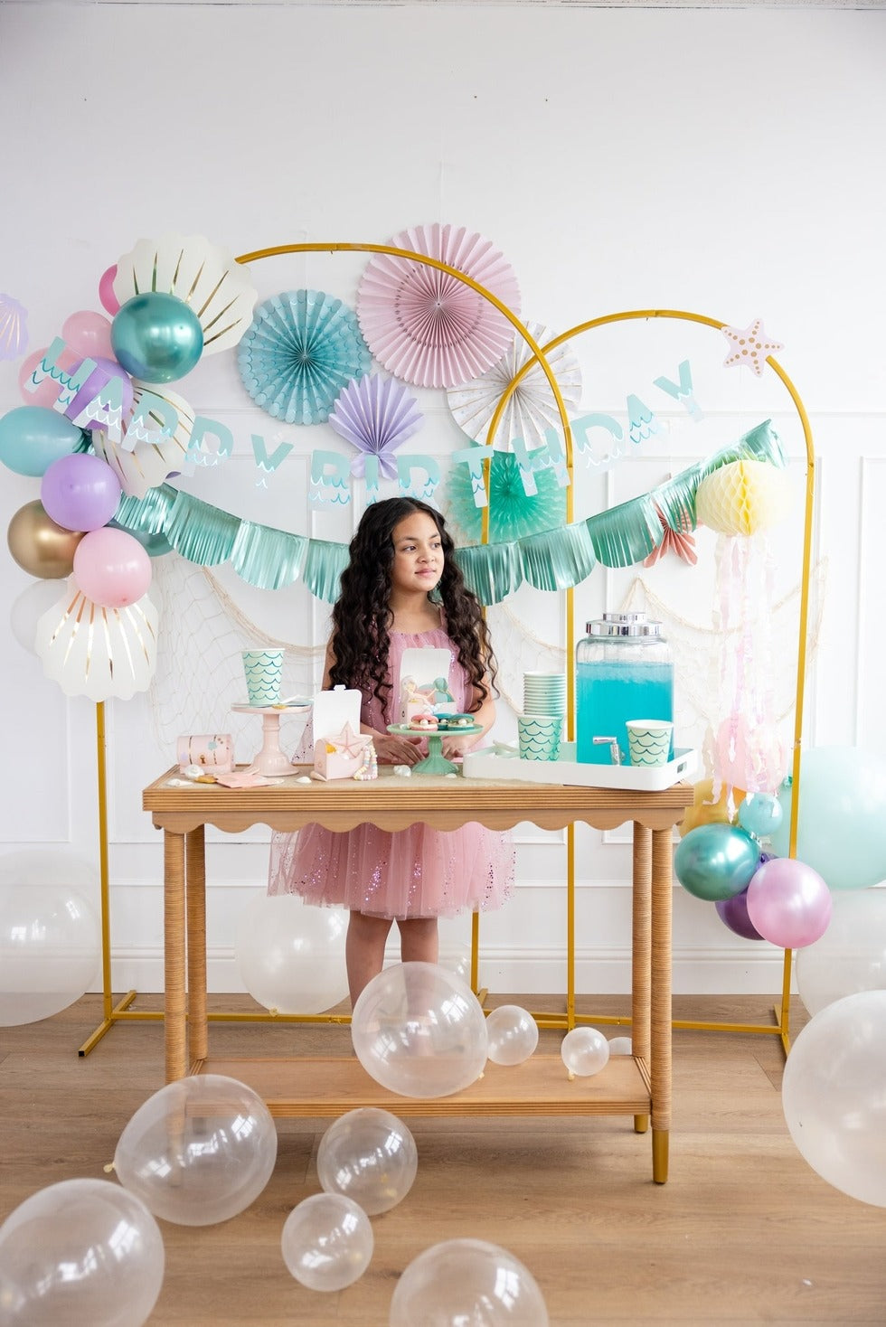 Pastel mermaid birthday party decorations with balloons and a girl in a pink dress from Parte Haus party supply store in Bethesda Maryland