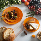 orange plastic plates with salad cheese and fruit on a marble table for brunch from Parte Haus party supply store in Bethesda MD