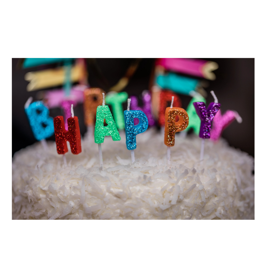 multicolor glitter birthday candles on white coconut cake birthday theme from Parte Haus party supply store in Bethesda Maryland