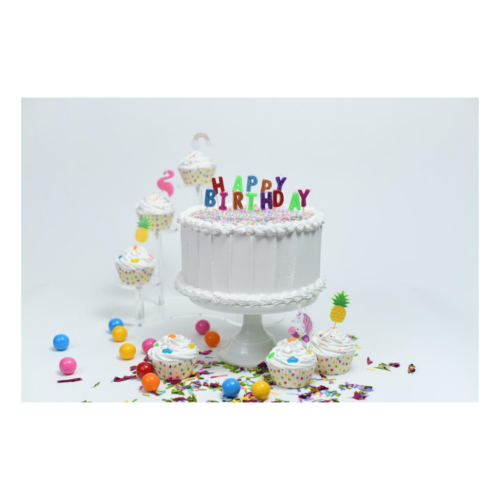 White birthday cake with colorful happy birthday candles and cupcakes for birthday from Parte Haus party supply store in Bethesda Maryland