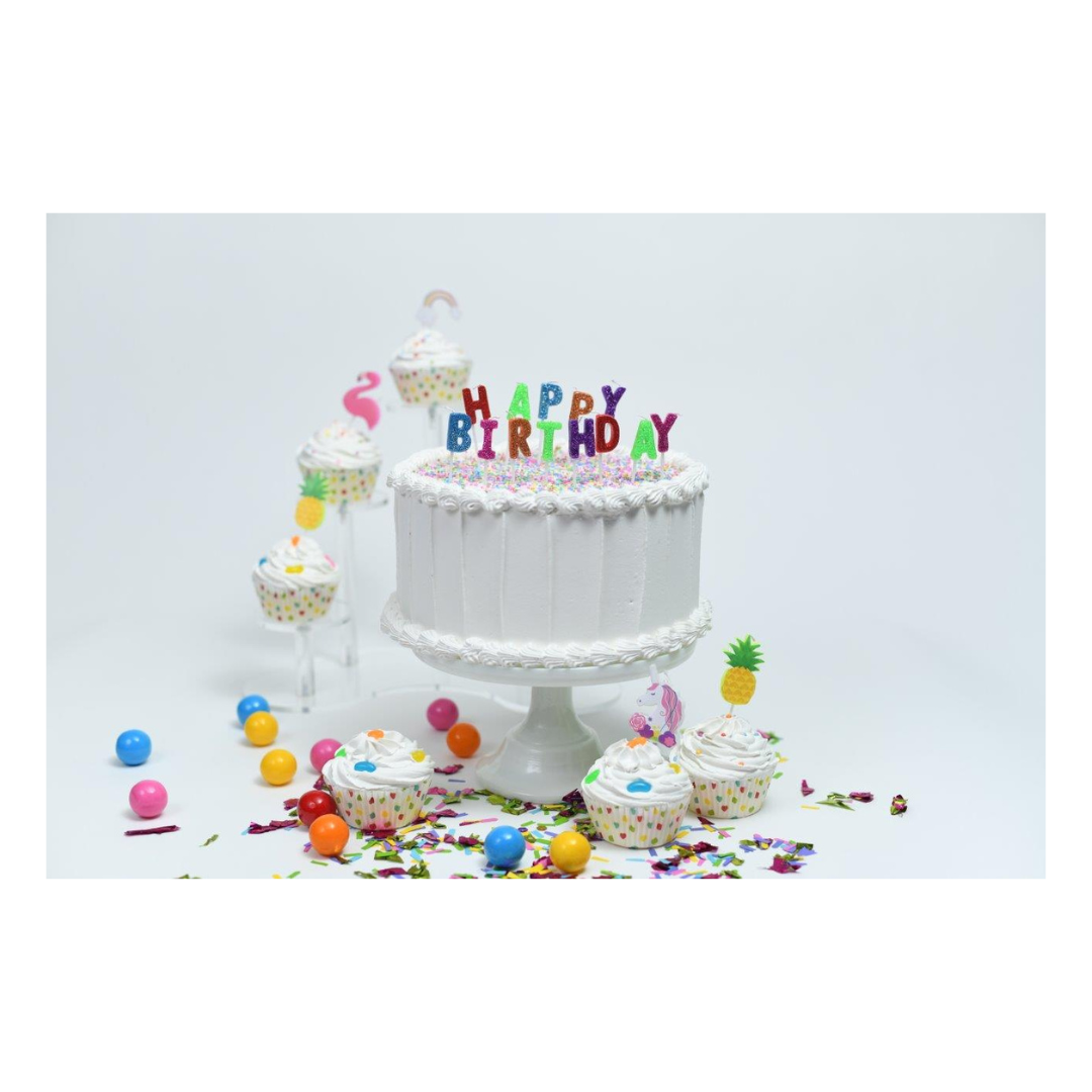 White birthday cake with colorful happy birthday candles and cupcakes for birthday from Parte Haus party supply store in Bethesda Maryland