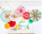 Colorful birthday decorations paper fans and garlands with cake and hats birthday theme from Parte Haus party supply store in Bethesda MD
