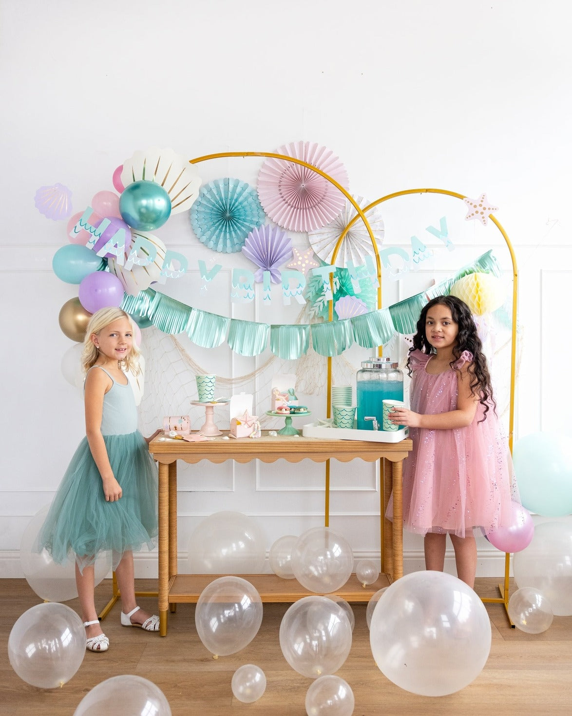 Pastel birthday decorations with balloons and two girls in dresses under Happy Birthday banner from Parte Haus party supply store in Bethesda Maryland
