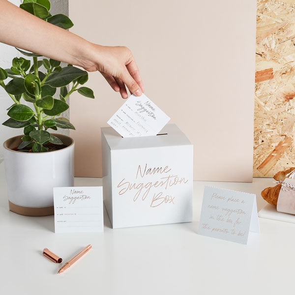 White baby name suggestion box with gold writing and cards for baby shower from Parte Haus party supply store in Bethesda Maryland