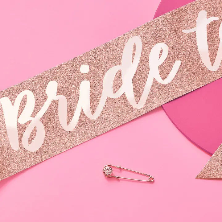 Rose gold bride to be sash with white script and safety pin bachelorette from Parte Haus party supply store in Bethesda MD