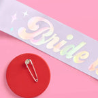 White iridescent bride sash with shiny text and pin for bachelorette from Parte Haus party supply store in Bethesda Maryland