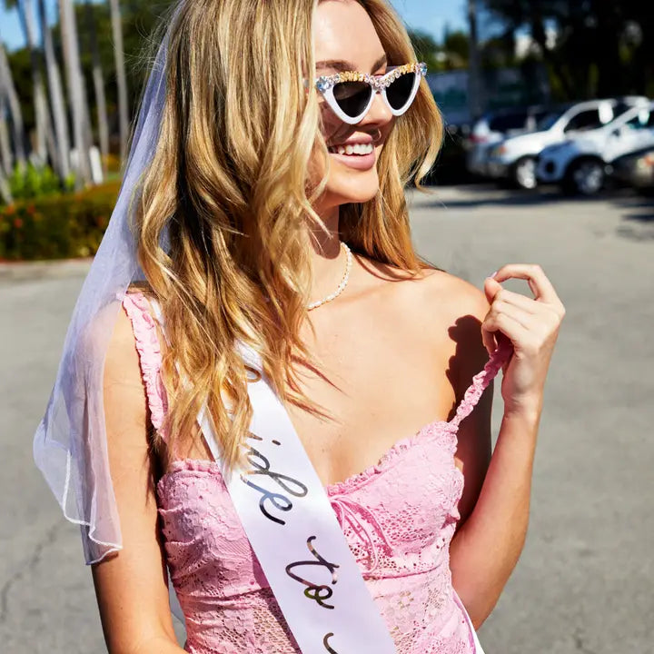 Rose gold bride to be sash worn by smiling woman at bachelorette from Parte Haus party supply store in Bethesda Maryland
