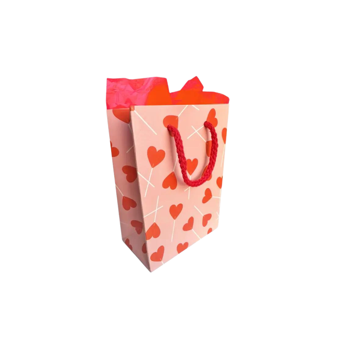 Pink gift bag with red heart prints and tissue for Valentine’s Day from Parte Haus party supply store in Bethesda MD.