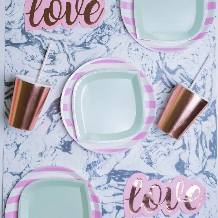 Pink and white candy stripe dinner plates with rose gold cups for love themed event from Parte Haus party supply store in Bethesda MD