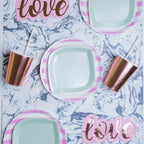 Pink and white candy stripe dinner plates with rose gold cups for love themed event from Parte Haus party supply store in Bethesda MD