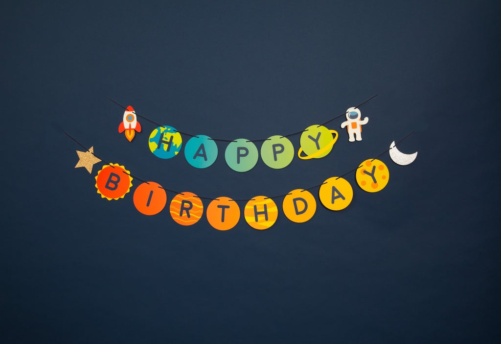 Colorful space theme birthday banner with planets rocket and astronaut from Parte Haus party supply store in Bethesda MD