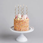 Gold curly candles on sprinkled birthday cake from Parte Haus party supply store in Bethesda MD