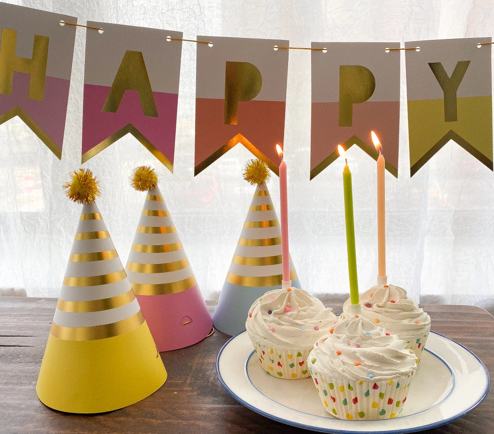 Rainbow birthday banner pastel and gold party hats with cupcakes birthday theme from Parte Haus party supply store in Bethesda Maryland