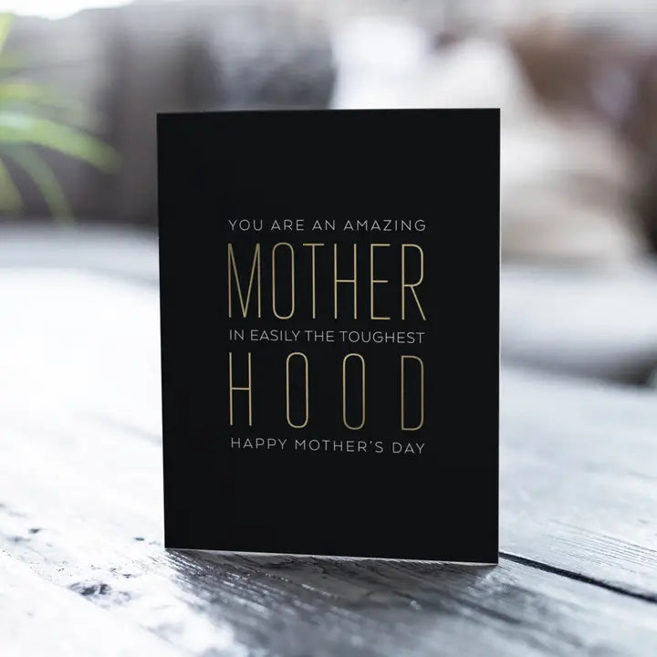 Black Motherhood greeting card with gold text for Mother’s Day from Parte Haus party supply store in Bethesda Maryland.