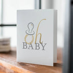 White and gold baby announcement card with pacifier for baby shower from Parte Haus party supply store in Bethesda Maryland