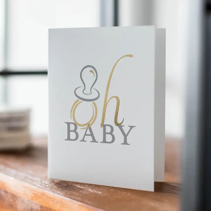 White and gold baby announcement card with pacifier for baby shower from Parte Haus party supply store in Bethesda Maryland