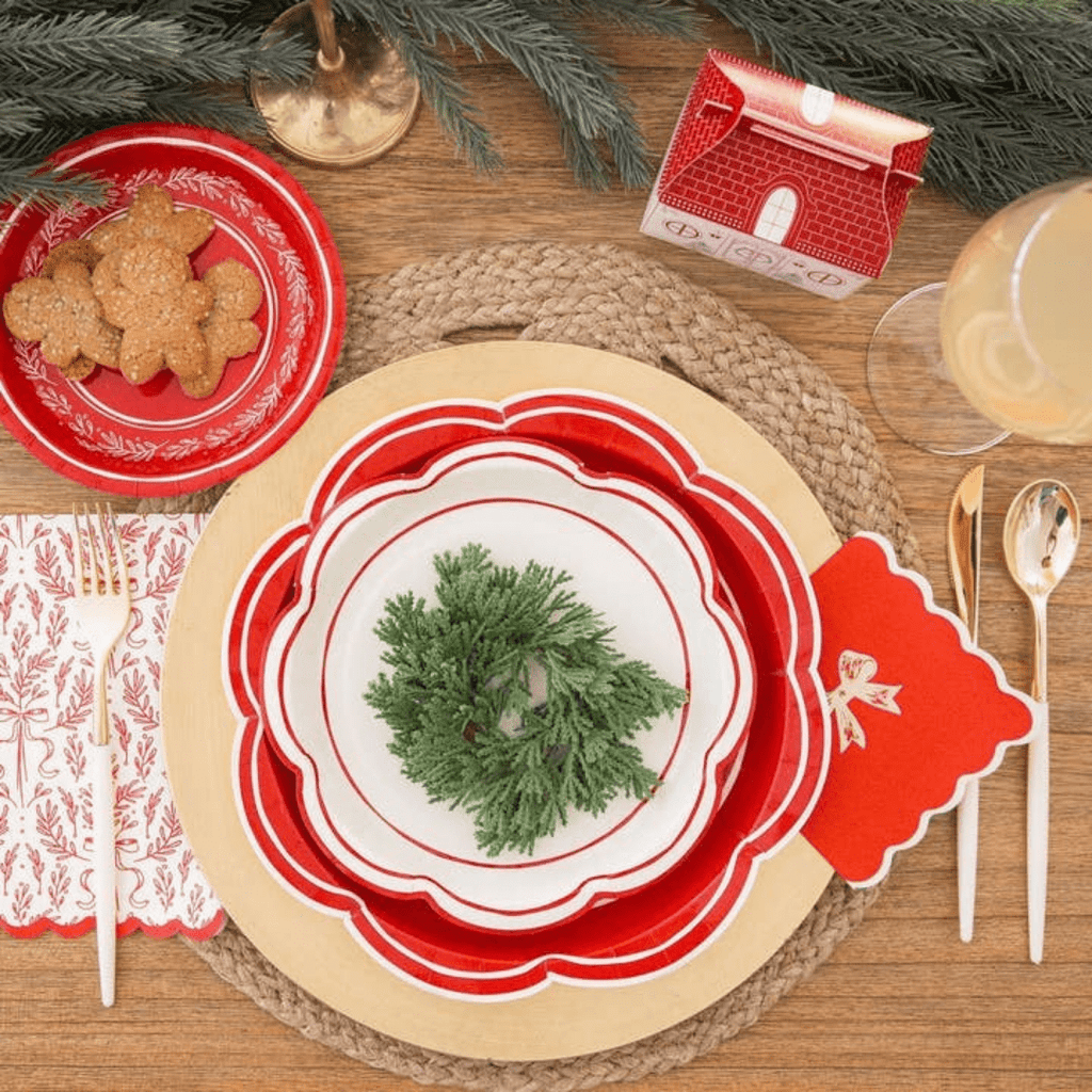 Red and white scalloped plates with holiday greenery place setting for Christmas from Parte Haus party supply store in Bethesda Maryland