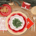 Red and white scalloped plates with holiday greenery place setting for Christmas from Parte Haus party supply store in Bethesda Maryland