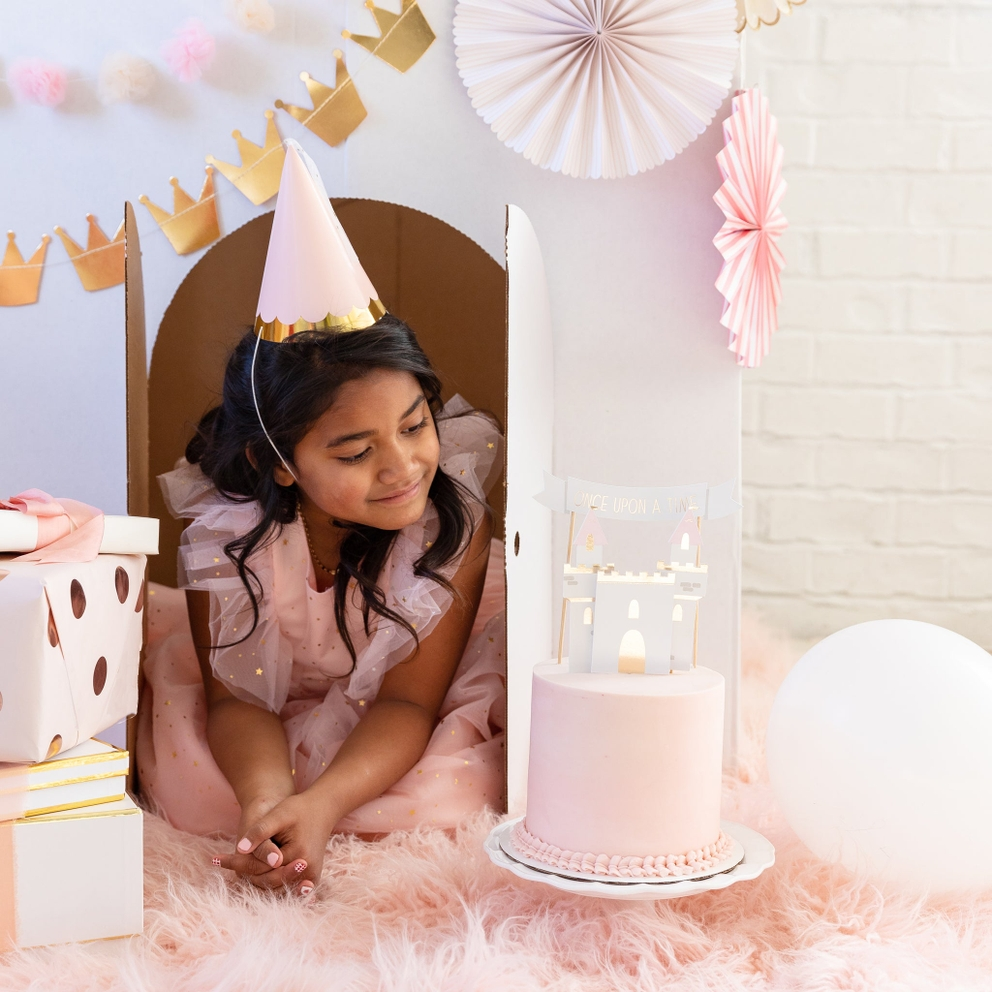 Pink princess party hat with gold trim worn by girl in a castle playhouse for birthday from Parte Haus party supply store in Bethesda MD