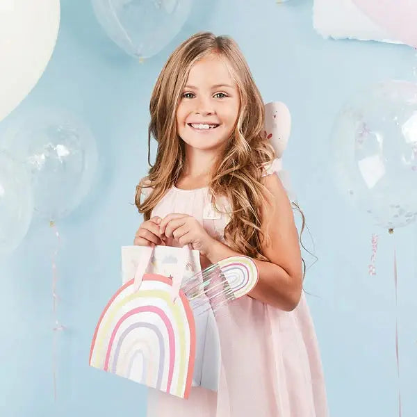 Rainbow pastel party bags with handles held by a smiling child birthday theme from Parte Haus party supply store in Bethesda MD