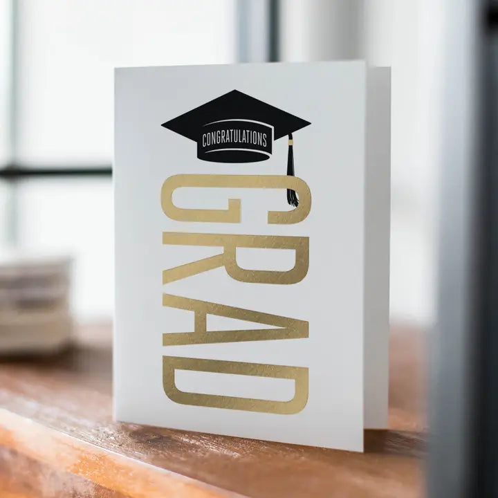 White and gold graduation greeting card with cap design for graduation from Parte Haus party supply store in Bethesda Maryland