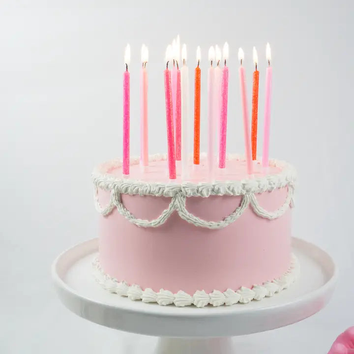 Tall pink gradient birthday candles on a white frosted cake for celebration from Parte Haus party supply store in Bethesda Maryland