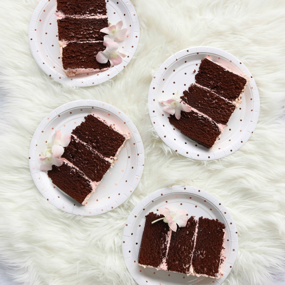 White and rose gold dot dinner plates with chocolate cake slices for birthday from Parte Haus party supply store in Bethesda Maryland