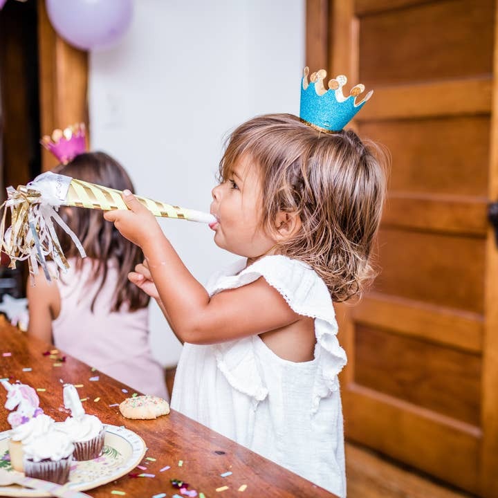 Blue crown headband girl with gold party blower at kids birthday from Parte Haus party supply store in Bethesda Maryland