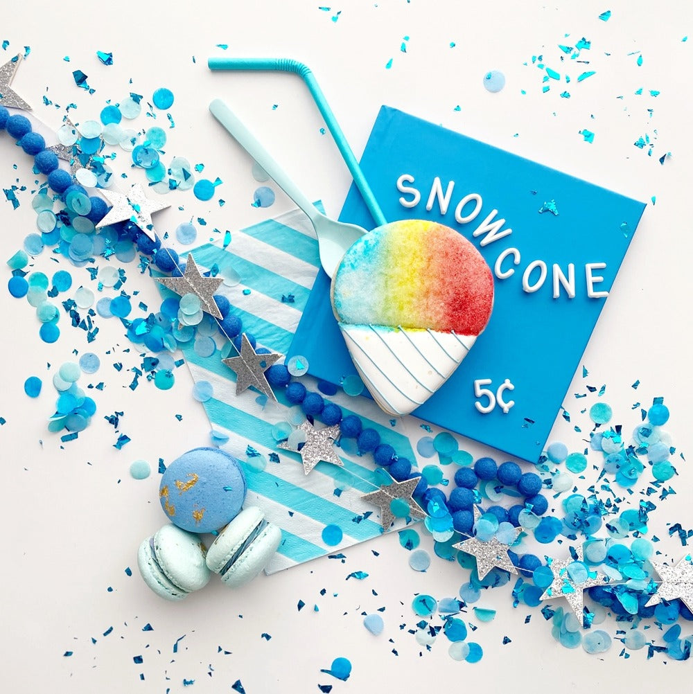 Blue snowcone sugar cookie with pastel macarons and star garland for birthday from Parte Haus party supply store in Bethesda MD