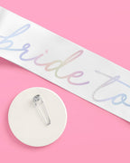 White iridescent bride sash with safety pin for bridal shower from Parte Haus party supply store in Bethesda MD