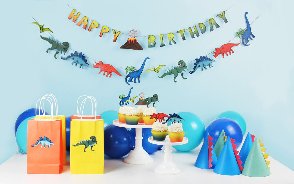 Colorful dinosaur birthday decorations with party hats cupcakes balloons and gift bags from Parte Haus party supply store in Bethesda Maryland