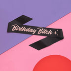 Black birthday sash with pink glitter text on pastel background birthday theme from Parte Haus party supply store in Bethesda MD