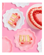 Pink heart shaped cake with swirl icing and matching scalloped plates for birthday theme from Parte Haus party supply store in Bethesda MD.