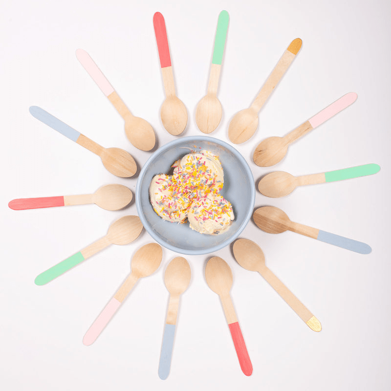 Color dipped wooden ice cream spoons arranged around a blue bowl dessert birthday from Parte Haus party supply store in Bethesda Maryland