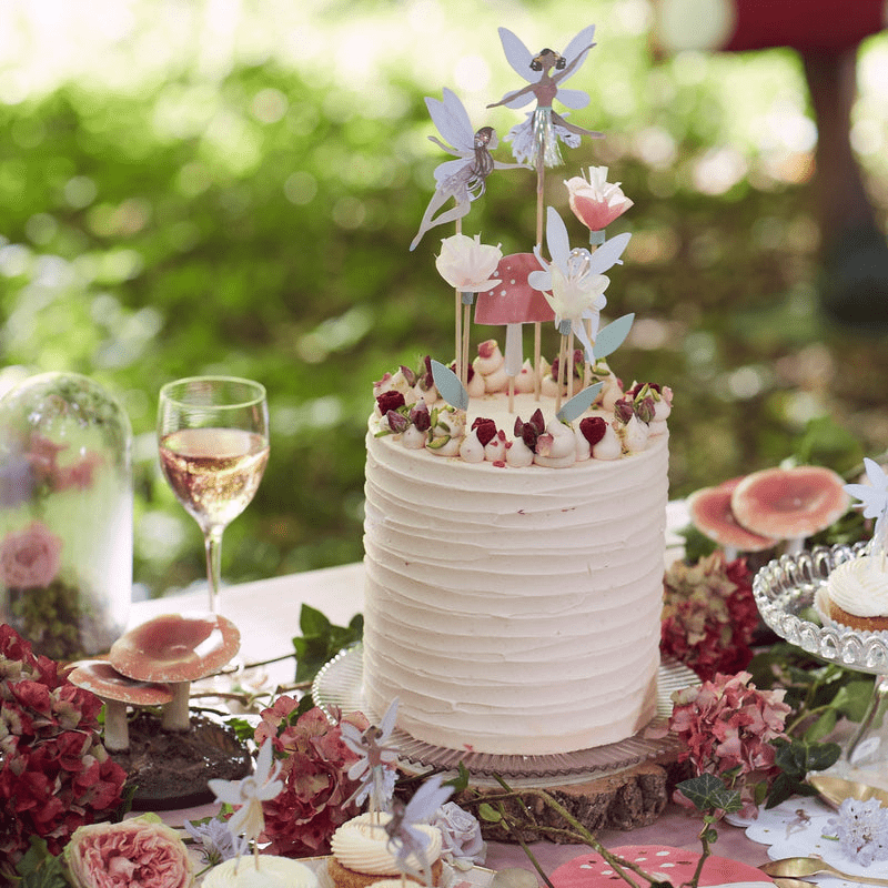 White fairy themed cake with flower and fairy toppers garden birthday from Parte Haus party supply store in Bethesda MD