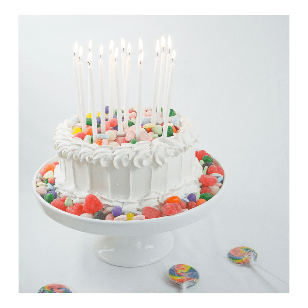 White cake with colorful candy decorations and tall birthday candles for birthday from Parte Haus party supply store in Bethesda MD