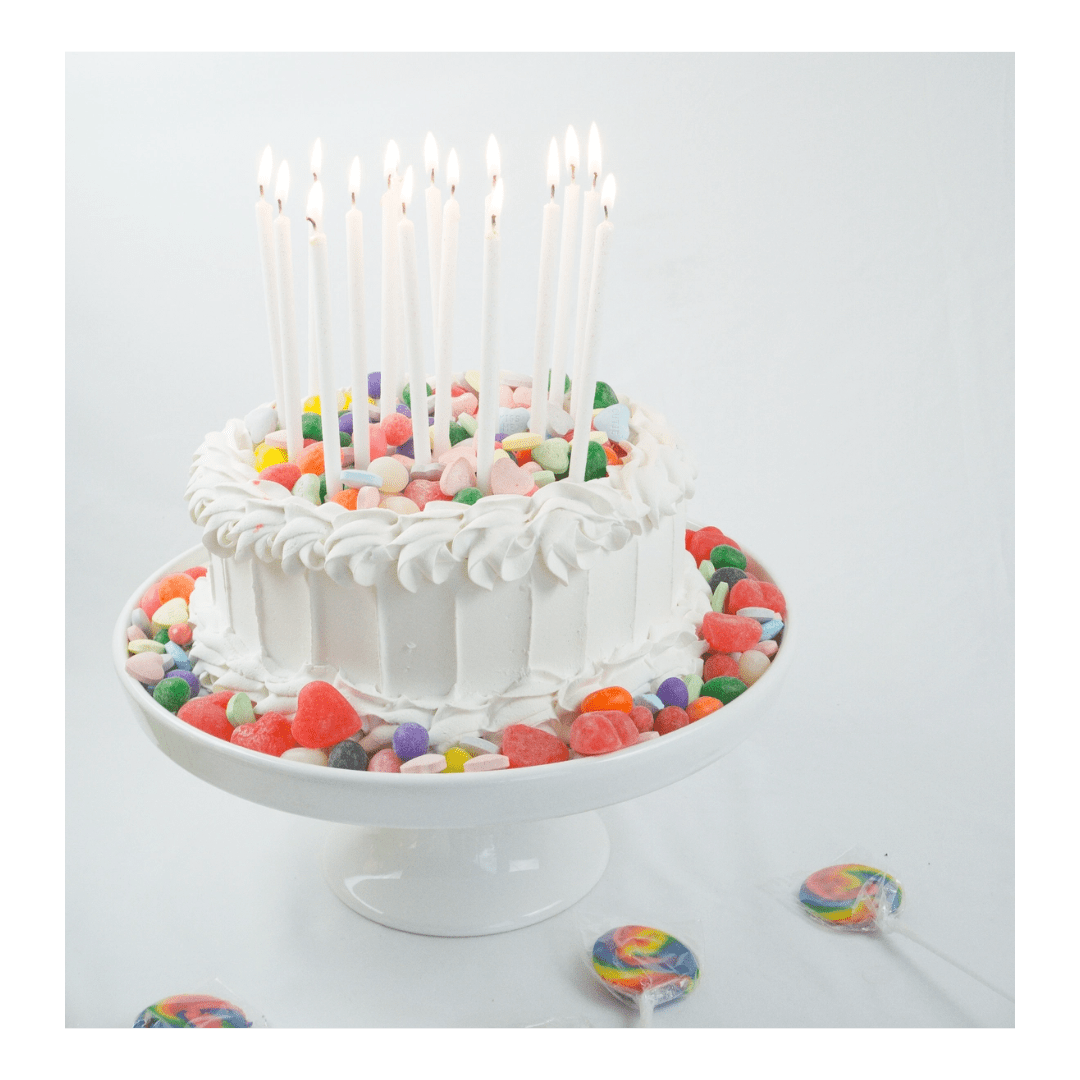 White cake with colorful candy decorations and tall birthday candles for birthday from Parte Haus party supply store in Bethesda MD