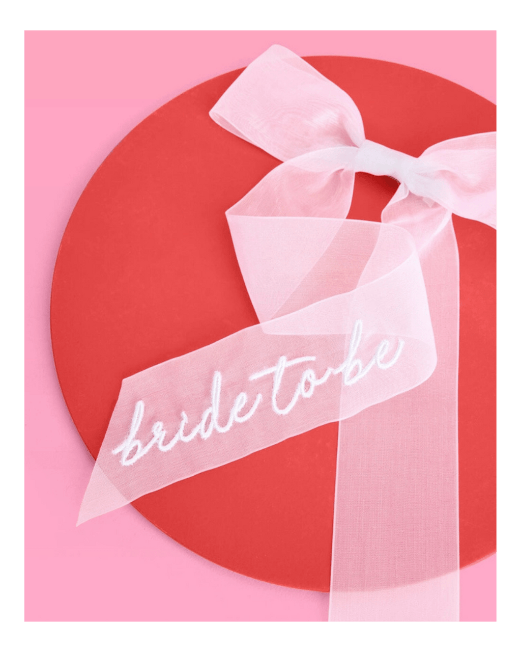 White bride to be bow bridal shower sash on pink and red background from Parte Haus party supply store in Bethesda MD.