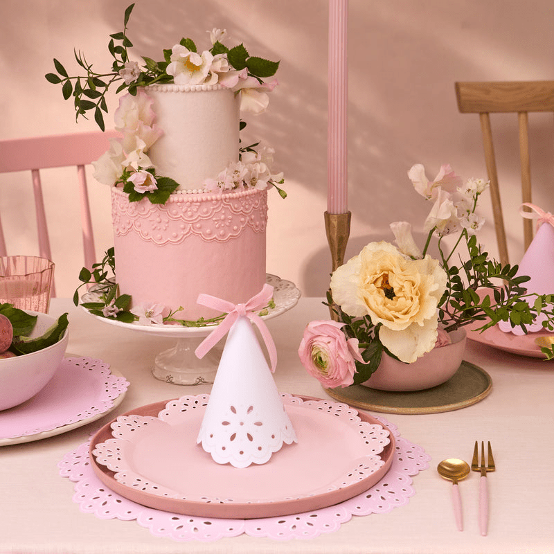 Pink and white birthday table decor with floral cake and paper party hats from Parte Haus party supply store in Bethesda Maryland