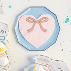 Pink heart napkin with gold bow design for Easter on blue plate from Parte Haus party supply store in Bethesda MD