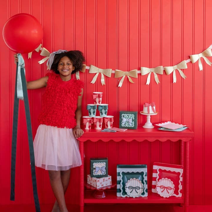 Red and gold birthday decorations with a smiling girl and festive table from Parte Haus party supply store in Bethesda Maryland