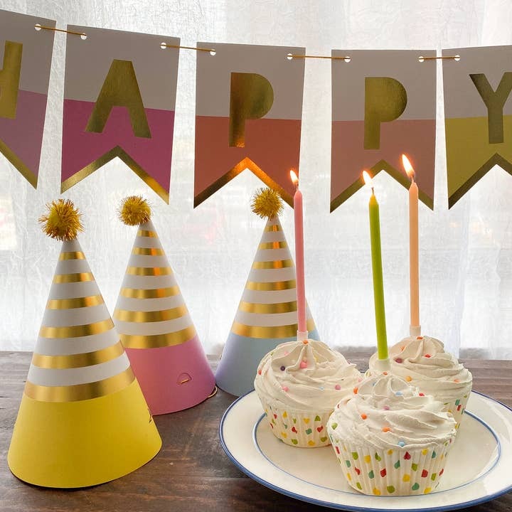 Pastel and gold striped party hats cupcakes with candles and HAPPY banner birthday theme from Parte Haus party supply store in Bethesda Maryland